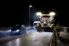 Bilde av asfaltlegging og trafikk nær asfaltarbeiderne om natten.