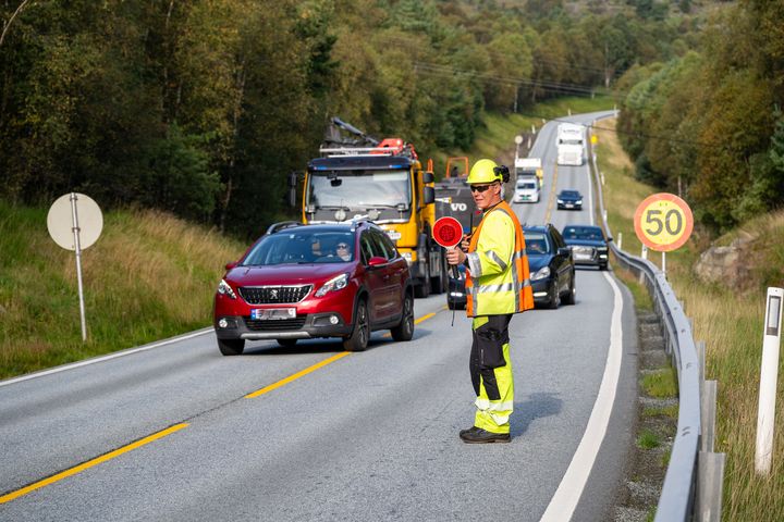Foto av trafikkdirigent og kø i sommervær