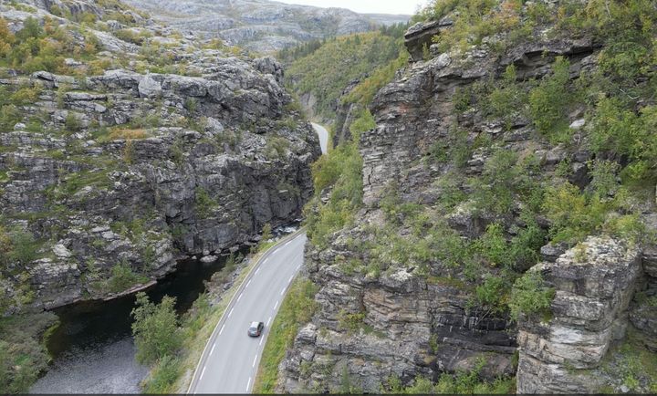 Bildet er et dronebilde av E45 der vegen slynger seg langs Eibyelva igjennom  en canyon med stupbratte fjell på begge sider. Bildeteksten sier, Flaskehalsen: Dagens E45 gjennom kløfta følger en naturlig elvecanyon. Den skjærer seg dypt ned i fjellet fra Finnmarksvidda mot Alta. Fjellet har dårlig kvalitet og det går ofte snøskred, sørpeskred og steinras som gir stengt veg. Nå skal strekningen legges i tunnel.