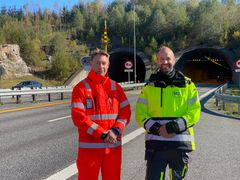 To menn står ved en firefeltsveg med to tunnelåpninger i bakgrunnen.