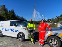 To menn står foran to arbeidsbiler med Smålenene bru i bakgrunnen.