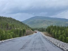 Bildet viser en lang slak bakke som nylig er asfaltert. Bilteteksten sier, Asfaltert: Store deler av den en mil lange vegstrekningen har fått asfalt. Vegen er 9,5 m bred og får fartsgrense 90 km/t.