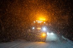 Brøytebil som køyrer i snøvêr og det er mørkt.