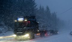 Vogntog som kjører i snøvær og det er mørkt.