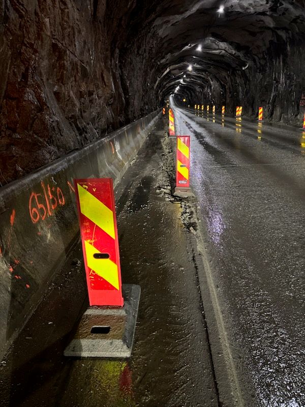 Bildet viser reflekser langs tunnellveggene inne i Nappstraumtunnelen. Bildeteksten sier, Hastigheten satt ned til 50 km/t i deler av tunnelen . Refleks med «sebra» striper for å markere overgang mellom vei og tunnelvegg. Tiltakene gjør det mulig med møtende trafikk fra begge sider.