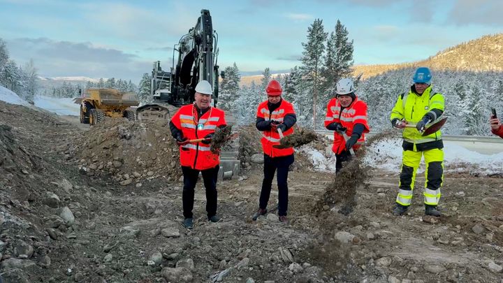 Bildet viser fire personer som kaster grus fremover med hver sin spade. Bildeteksten sier: Ivrig firkløver i synkronisert spadedans: Fra venstre; Ordfører i Alta kommune, Jan Martin Rishaug (Sp), samferdselsminister Jon-Ivar Nygård (Ap), assisterende vegdirektør, Ove Myrvåg og prosjektleder for Anlegg Nord AS, Ståle Kjellmann.