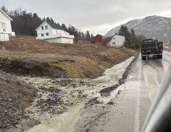 Bildet viser hvordan vannet fra bekken har bygd opp en rygg av løsmasser der den møter dagens E10 ved Hårvik i Tjeldsund. Bilteteksten sier, Vann og løsmasser: Dagens E10 kan få skader dersom bekken ved Hårvik i Tjeldsund ikke blir lagt i rør under vegen.