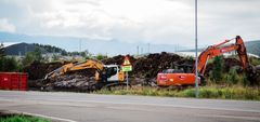 Bildet viser to gravemaskiner som har begynt å jobbe med riggområdet for utbyggingen. Bildeteksten sier, Det nærmer seg byggestart for E10 Evenes Flyplasskryss. Nå er forberedene arbeid i gang.