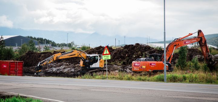 Bildet viser to gravemaskiner som har begynt å jobbe med riggområdet for utbyggingen. Bildeteksten sier, Det nærmer seg byggestart for E10 Evenes Flyplasskryss. Nå er forberedene arbeid i gang.