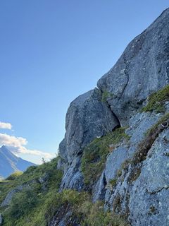 Bildet viser hvordan den store steinblokken henger skrått i en fjellvegg oppe i Karitinden: Bildeteksten sier, Henger foreløpig godt: Det er ingen umiddelbar fare for at steinblokkene i Karitinden skal komme ned av seg selv. Men Statens vegvesen ønsker å fjerne risikoen for at det skjer.