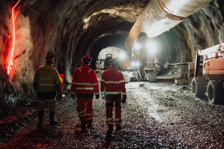 Bilde av tre menn i anleggsklær som går innover Røldalstunnelen.