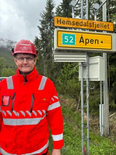Bildet viser prosjektleder i Statens vegvesen Pål-Steinar Karlsen. Han står i oransje klær fra Statens vegvesen ved et skilt hvor det står Hemsedalsfjellet.