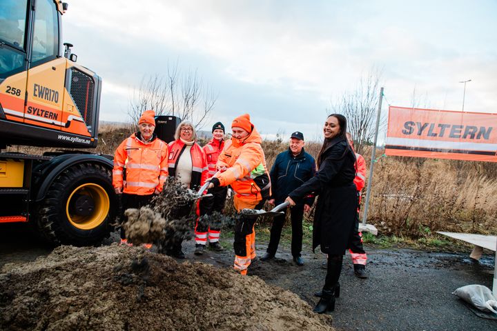 Bildet viser samferdselsministeren og en lærling fra Syltern AS som hiver sand og jord med hver sin spade. bildeteksten sier, Lærling hos Syltern AS, Steffen Øverli Vold fra Snåsa fikk æren av å ta første spadetak i prosjektet E10 Evenes Flyplasskryss sammen med samferdselsminister Kamzy Gunaratnam (Ap)