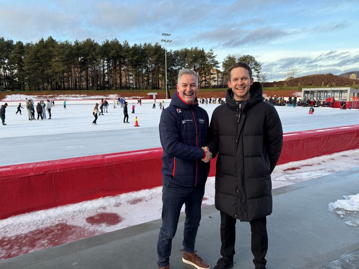 Generalsekretær Jarle Blindheim i NSF sammen med grunnlegger av Baardsen Sport, Joachim Baardsen. I bakgrunnen ser man et yrende folkeliv på Valle Hovin stadion søndag ettermiddag.