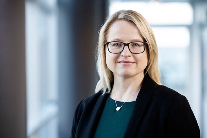 Portrettbilde av en kvinne med lyst mellomlangt hår og briller, med sorte klær.