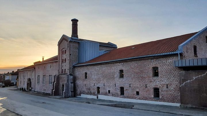 Fasaden på Fredrikstad bryggeri i Østfold vises mot lysblå himmel i soloppgang eller solnedgang