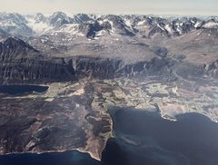 Flyfoto av Pollen. Nergaardhuset ligger ved foten til det bratte Pollfjellet i Rundfjellmassivet, som ligger rett øst for Lyngsalpans høyeste topp og største isbreområde.