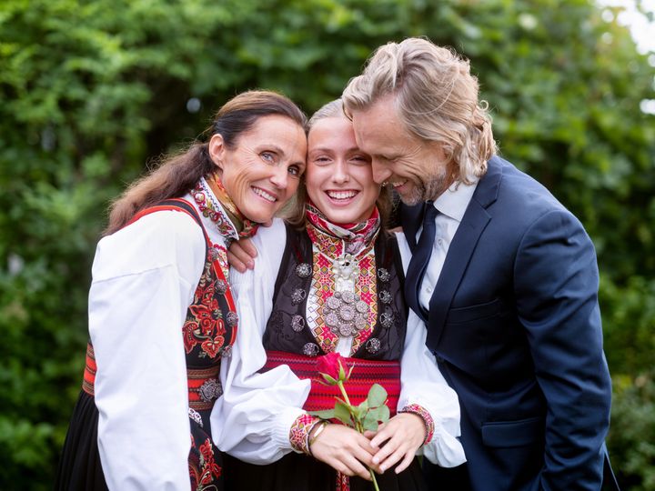 Foreldre sammen med datteren på konfirmasjonsdagen. Gjengen klemmer hverandre.