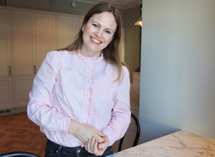 Portrett av blid kvinne med langt hår i rosa skjorte.