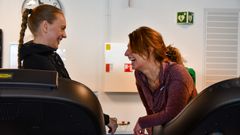 Ei dame gliser til personleg trenar på tredemølle.