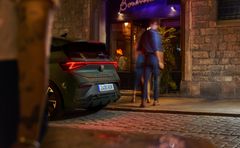 Bildet viser elbilen CUPRA BORN VZ bakfra parkert utenfor en restaurant