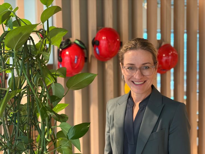 Elin Vigrestad, ved grønn plante og med hjelmer i bakgrunn