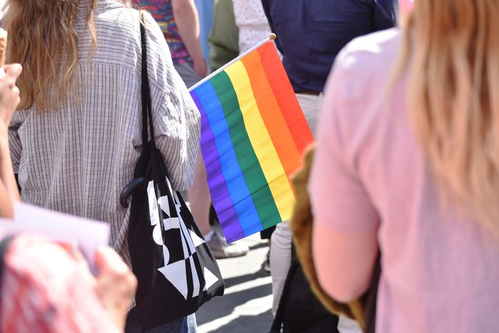 Gruppe med mennesker som markerer Pride med et regnbueflagg
