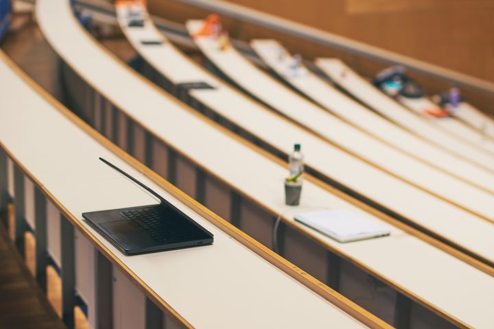 Tomt auditorium på universitetet med en laptop liggende på pulten