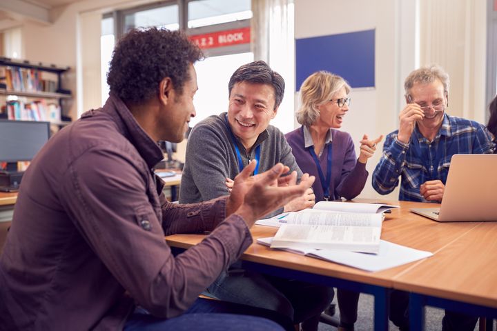 En gruppe lærere og studenter sitter rundt et bord i et bibliotek