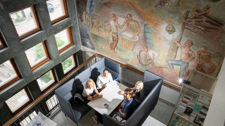 Fire studenter sitter ved et bort på Psykologisk institutt, UiO, og ser opp på fotografen