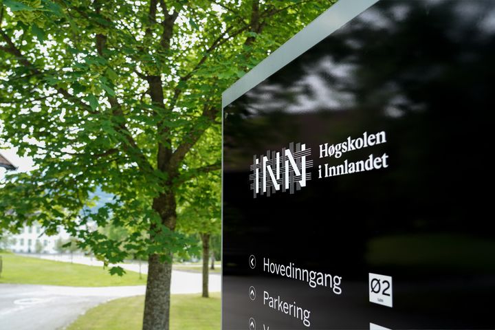 Utendørskilt med logoen til Høgskolen i Innlandet på svart bakgrunn