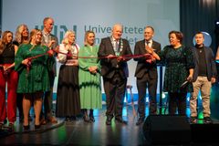 Rektor Peer Jacob Svenkerud, statsråd Oddmund Hoel, ordførere i universitetets vertskommuner, studenter og konferansier Else Kåss Furuseth på scenen under en symbols snorklipping.