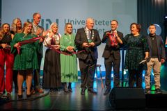 Rektor Peer Jacob Svenkerud, statsråd Oddmund Hoel, ordførere i universitetets vertskommuner, studenter og konferansier Else Kåss Furuseth på scenen under en symbols snorklipping.