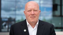 Mann i mørk dress og hvit skjorte.