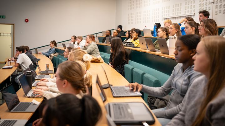 Studenter følger med i forelesning i et auditorium