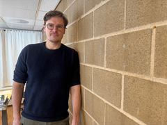 Hatfield lener seg mot en vegg og ser i kameraet