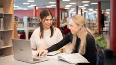 To jenter som studerer på et bibliotek.