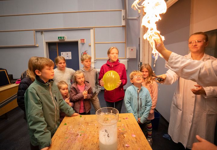 Barn som ser på forsker med ild i hånda på laboratoriet