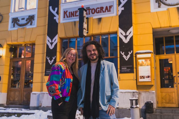 Kvinne og mann foran en gul og ærverdig eldre kinobygning.