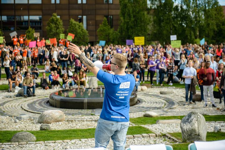 Student med megafon taler engasjert til masse studenter i forbindelse med studiestart på sensommeren.