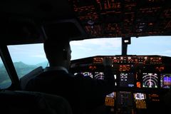 En person sitter i en flysimulator med lysende instrumentpaneler foran seg.