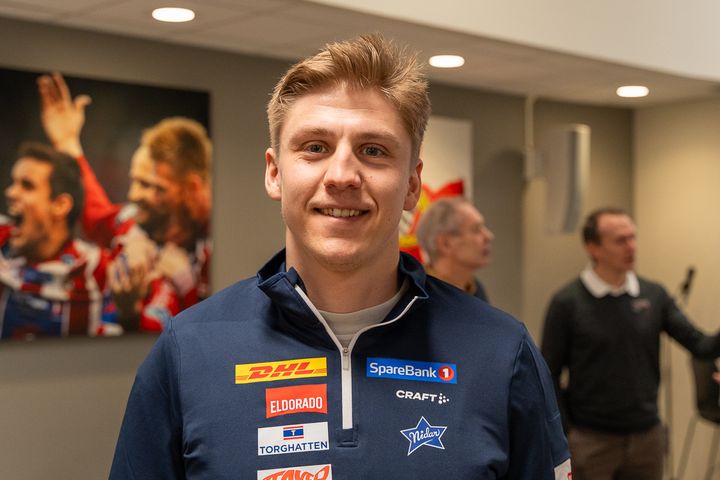 Gutt som smiler med genser med mange sponsor-logoer på