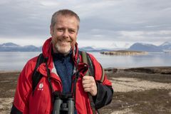 Mann står i turklær ute foran en fjord