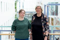 To kvinner står sammen ved et rekkverk i en moderne bygning.