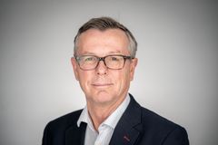 Portrett av en mann med briller i dress.