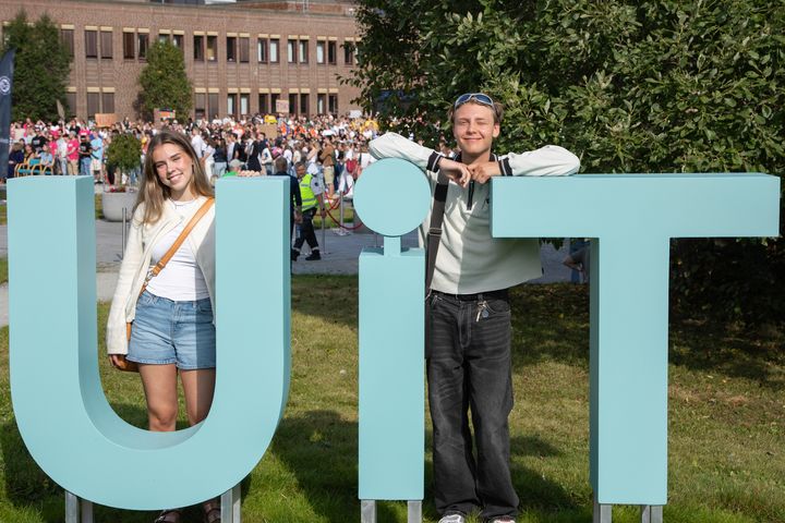 to studenter som står ved tre store bokstaver