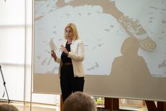 En kvinne holder en presentasjon foran et lerret som viser et skip i islagt vann.