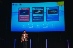 En kvinne som står på en scene og presenterer foran en skjerm med tre kort som viser forskjellige typer dyr og deres egenskaper.