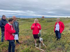 En gruppe mennesker diskuterer i et landskap.