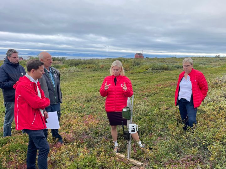 En gruppe mennesker diskuterer i et landskap.